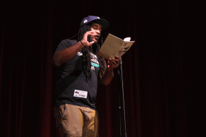 Jovan Mays reads a poem to a theatre full of English students.
